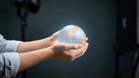 Hands holding glowing transparent sphere with soft light emanating from within against dark background. Concept for innovation, ideas, energy, and futuristic technology.