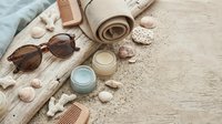 Spa wellness flat lay with natural skincare products, wooden combs, sunglasses and seashells on rustic wood background for relaxation and beauty routine.