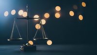 Scales of justice with warm bokeh lights creating atmospheric legal concept for law firm branding and judicial system presentations.