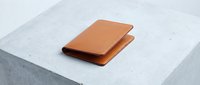 Premium leather wallet in warm brown color placed on modern concrete surface for luxury accessories and fashion photography.