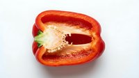 Red bell pepper sliced in half, showing fresh seeds and white interior on isolated white background, ready for culinary, food styling, recipe, and design projects.
