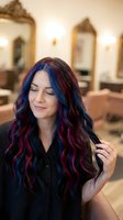 Young woman with long wavy hair featuring vibrant blue and magenta highlights in a salon setting. Hair coloring, fashion, and beauty styling concepts.