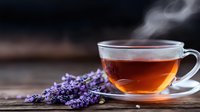 Steaming cup of herbal tea with fresh lavender flowers on rustic wooden table, moody lighting creates calming atmosphere for wellness and relaxation.