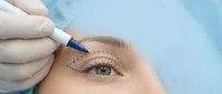 Cosmetic surgeon marking eyebrow area with pen before permanent makeup procedure on young woman face for beauty enhancement treatment.