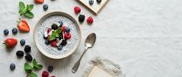 Chia seed pudding topped with fresh berries, mint leaves, and served in a white bowl on marble surface for healthy breakfast or dessert recipes.
