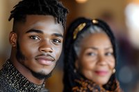 Young African American man with dreadlocks and older woman smiling together in warm indoor setting representing family bonds and generational connection.