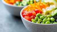 Fresh poke bowl with edamame beans, carrots, tomatoes and avocado served in gray ceramic bowl on dark background. Healthy vegetarian lunch concept.