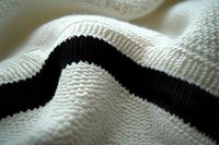 Close-up macro view of black and white knitted fabric texture with wavy pattern showing detailed wool or cotton fiber structure in soft lighting.