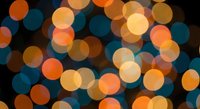 Abstract bokeh lights background with warm orange and cool blue circular light effects creating dreamy atmosphere for holiday decorations and festive designs.