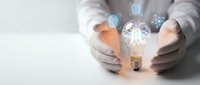 Business professional protecting glowing lightbulb with digital innovation icons representing creative ideas and technological solutions in modern workspace.