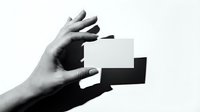 Hand holding blank white business card mockup against white background with dramatic shadow for branding presentation and corporate identity design.