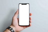 Hand holding modern smartphone with blank white screen against neutral gray background, perfect for app or website mockup presentation.