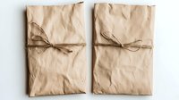Minimalist wrapped packages in brown kraft paper with simple twine bows on white background, sustainable eco-friendly gift wrapping concept for holidays and occasions.