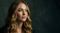 Young blonde woman with wavy hair in dramatic lighting against dark background for portrait photography and commercial projects.