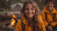 Cheerful young girl in yellow raincoat smiling at campfire during outdoor adventure. Warm evening atmosphere with bokeh lights and camping experience.