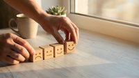Hands arranging wooden blocks with emoji faces from sad to happy on a table, symbolizing mood change, feedback, and customer satisfaction.