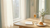 Cozy morning table with champagne, croissant, open notebook with Happy New Year text, and eucalyptus in vase by sunny window.