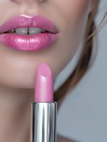 Close-up of glossy pink lips and matching lipstick in metallic silver tube, showcasing cosmetic product detail for beauty and makeup advertising.