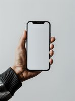 Hand holding modern smartphone with blank white screen against light background, wearing gray knit sleeve. Mockup for app and web design presentation.