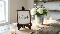 Rustic farmhouse home decor with blessed sign, white hydrangea flowers in galvanized bucket, candles on wooden table creating cozy atmosphere for interior design.
