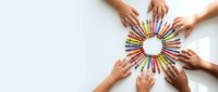 Diverse hands arranging colorful pencils in circular pattern on white background. Creative teamwork and collaboration concept for educational projects.