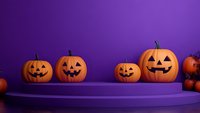 Carved Halloween pumpkins with happy faces displayed on purple platform against vibrant purple background, creating festive autumn holiday atmosphere.