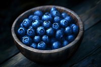 Fresh blueberries in wooden bowl on dark rustic table for healthy eating and organic food concepts.