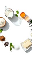 Fresh baking ingredients arranged on white background with milk, eggs, flour, butter and mint leaves for homemade cooking and culinary preparation.