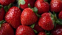 Fresh ripe strawberries with green leaves in macro view showing detailed texture and natural pattern of juicy red berries for food photography and design.