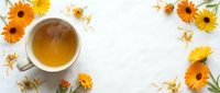 Herbal tea with dried chamomile and calendula flowers arranged on white background, overhead view for wellness and natural remedy designs.