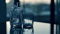 Crystal whiskey decanter and glass on reflective surface against dark moody background, dramatic lighting creates elegant atmosphere for luxury spirits.