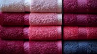 Stack of colorful leather samples in burgundy, pink and blue tones showing various textures and finishes for upholstery and craft projects.