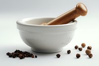 White ceramic mortar and wooden pestle with scattered whole peppercorns and ground black pepper on light background, traditional kitchen tools for spice grinding.