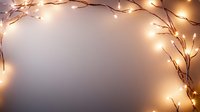 Glowing fairy lights and bare branches create magical frame border on neutral background, soft bokeh effect adds warmth and festive atmosphere for winter holiday designs.