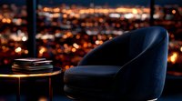 Luxurious navy velvet armchair against panoramic night cityscape with glowing lights, modern interior design setting with side table and books.