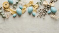 Pastel blue Easter eggs with yellow ribbon bow, willow branches, and eucalyptus on linen background, flat lay with copy space.