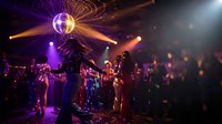 Vibrant nightclub scene with disco ball, colorful lights and dancing crowd enjoying party atmosphere on illuminated dance floor.