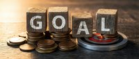 Wooden blocks spelling GOAL with coins and target, representing financial planning and achievement strategies for business success.