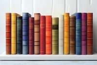 Row of vintage hardcover books in various colors standing on white wooden shelf, spines showing classic literature collection arranged neatly for library or home decor.