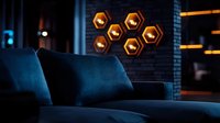 Modern living room interior with hexagonal wall lights glowing warm orange against dark walls, featuring navy blue velvet sofa in moody atmospheric lighting.