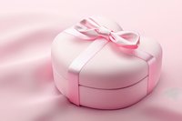 Heart shaped pink gift box with elegant satin ribbon bow on soft pink background. Romantic present for Valentine's day, wedding or anniversary celebration.