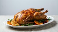 Golden roasted whole chicken with herbs and vegetables on white plate, perfect for holiday dinner, thanksgiving feast or family meal preparation.