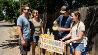 Young entrepreneurs operating a lemonade stand on a sunny residential street, featuring diverse teenagers selling refreshing beverages to neighborhood customers during summer.