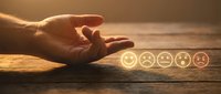 Male hand selecting excellent smiley face rating among poor to good feedback options on wooden surface, customer satisfaction and service quality evaluation concept.