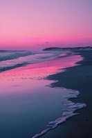 Dramatic pink sunset over ocean beach with gentle waves reflecting vibrant magenta sky, creating serene coastal landscape with distant cliffs and calm waters.