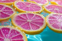 Magenta grapefruit slices with glitter coating and yellow rind floating on turquoise water, vibrant citrus background for summer beverage and food styling projects.