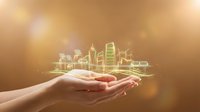 Hands holding glowing green cityscape with buildings and wind turbines, representing sustainable urban development, eco-friendly infrastructure, and renewable energy solutions for future cities.