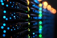 Network server rack with glowing LED indicators in dark data center, blurred bokeh lights creating atmospheric technology background for IT infrastructure.