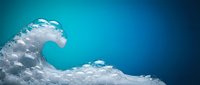 Dramatic ocean wave with white foam crashing against vibrant blue water background. Dynamic seascape showing powerful water motion and natural marine energy.