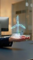 Holographic wind turbine floating above open palm in modern office setting representing renewable energy innovation and sustainable technology solutions.